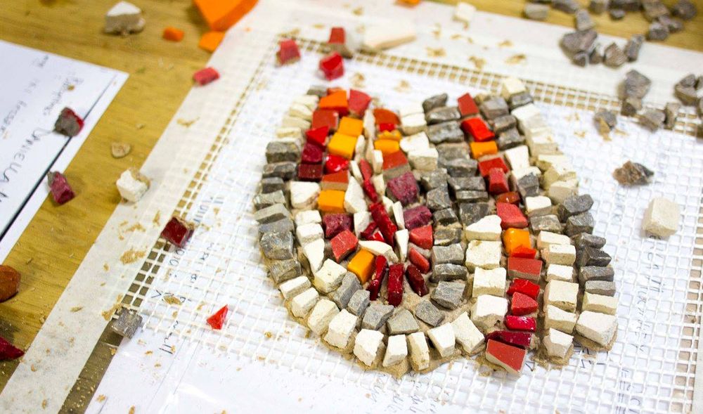A finished circular mosaic in warm red, orange and grey tones