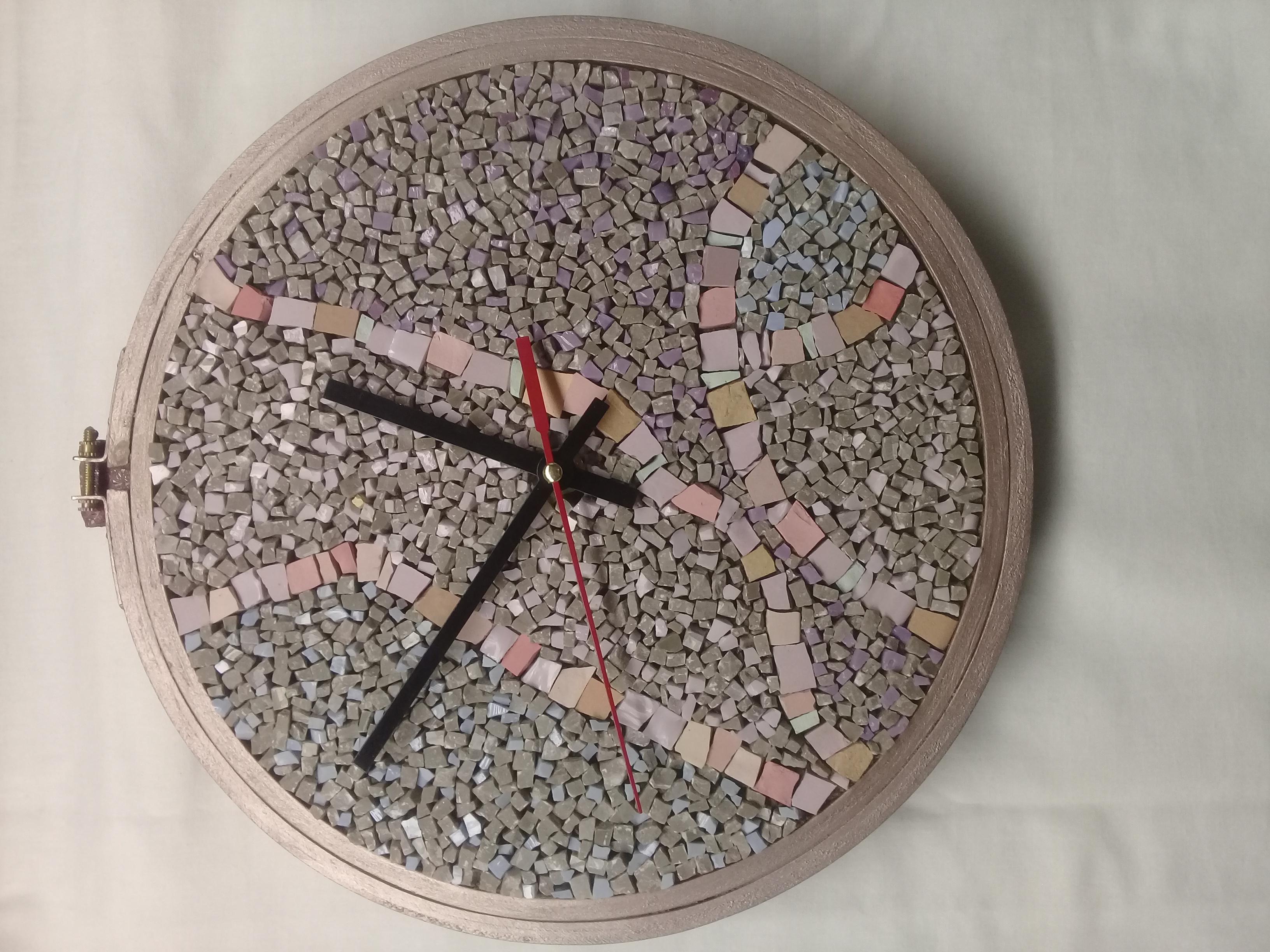 A finished mosaic wall clock in soft pink, grey and lilac tile
