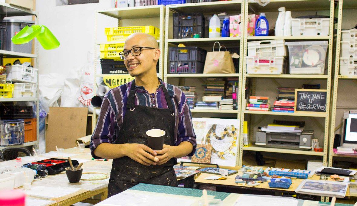 A GLU Creations maker smiling, holding a coffee cup in the studio