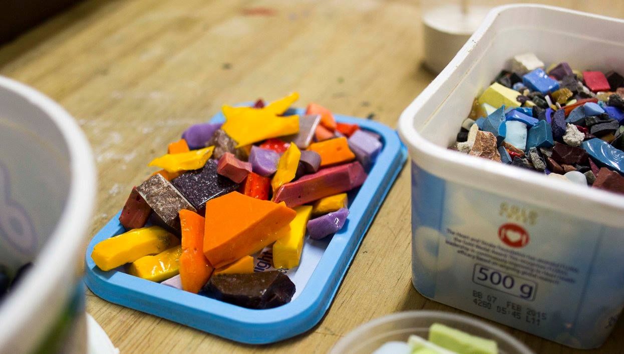A tray of colourful cut mosaic tile pieces alongside a bin of sorted material