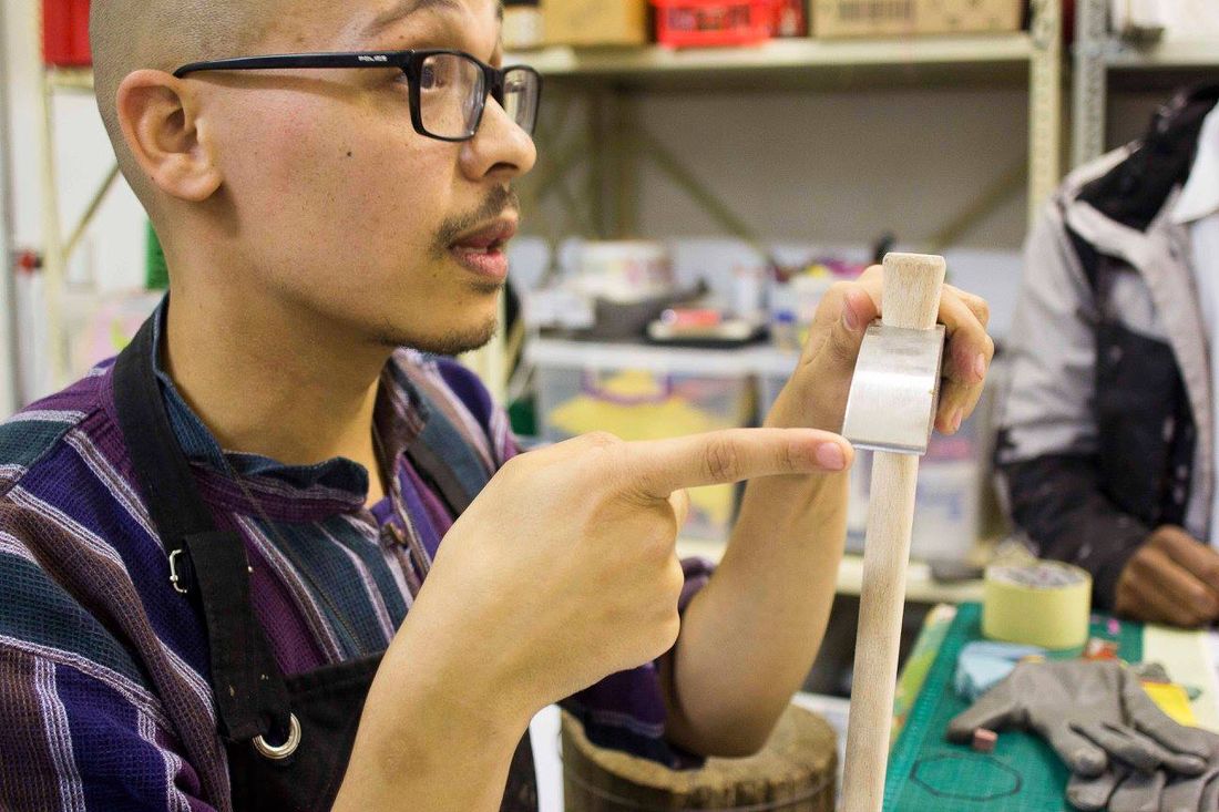 A studio member checking a wooden tile-cutting tool before working