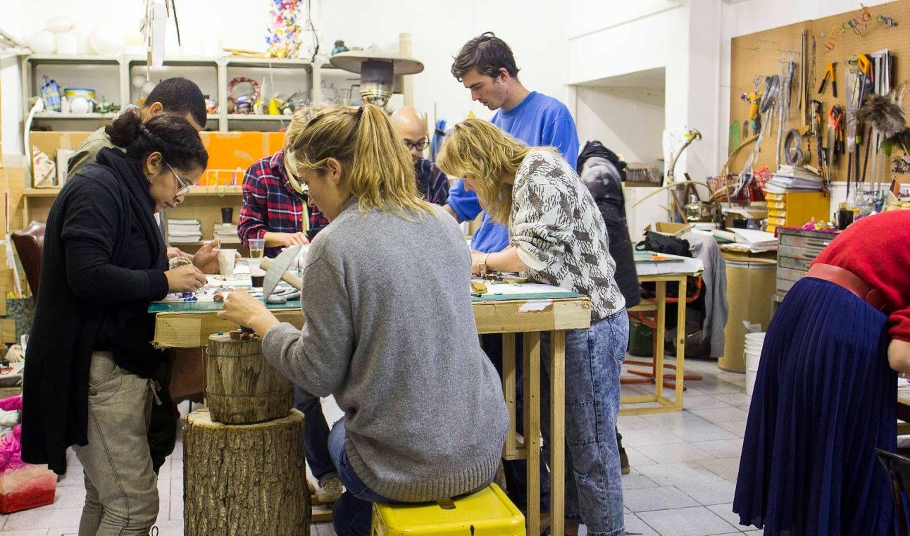 A group of studio visitors working at long tables inside the GLU Creations studio